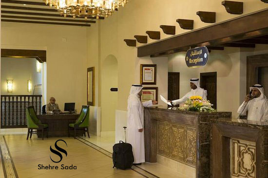 Hotel reception area where a guest is checking in at the counter, staff assisting, and another person working in the background